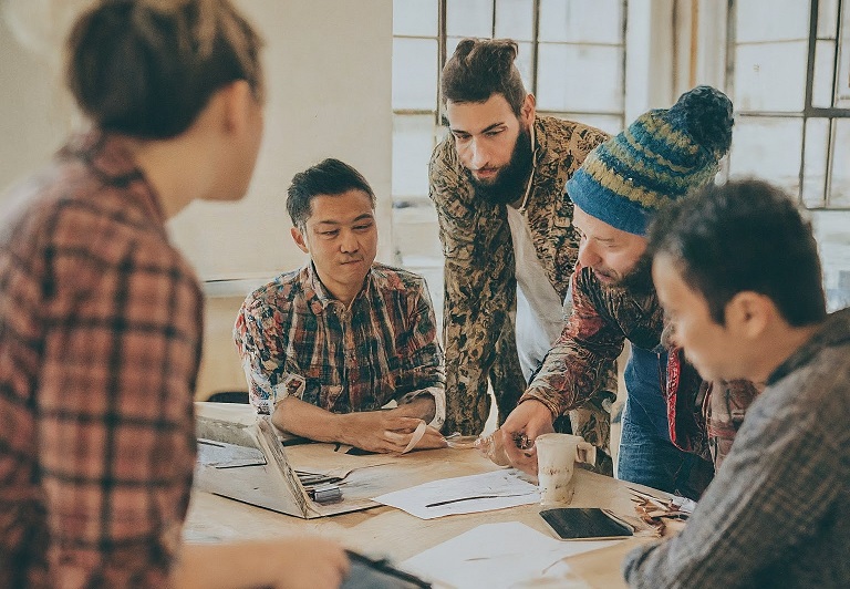 An AI-generated image of tech hipsters collaborating on a document. Worryingly, the only woman in the frame seems excluded.